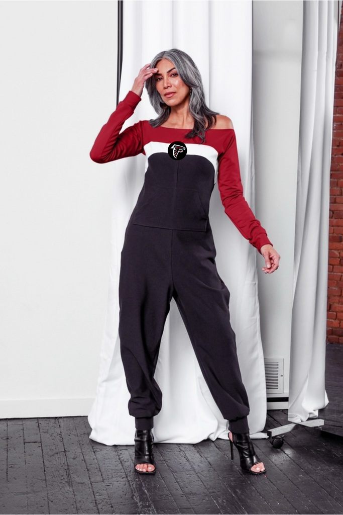 Off shoulder jumpsuit with red sleeves, white stripe, and black body with falcon logo on the center of the chest and front patch pockets. 