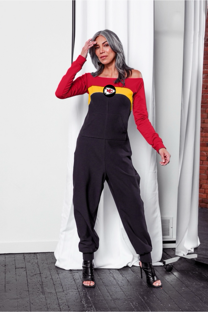 Off shoulder jumpsuit with red sleeves, gold stripe, black body, and Chiefs logo on the center of the chest with front patch pockets.